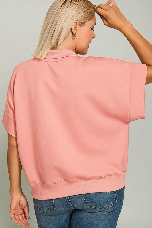 Person wearing a pink oversized top and blue jeans on a plain background