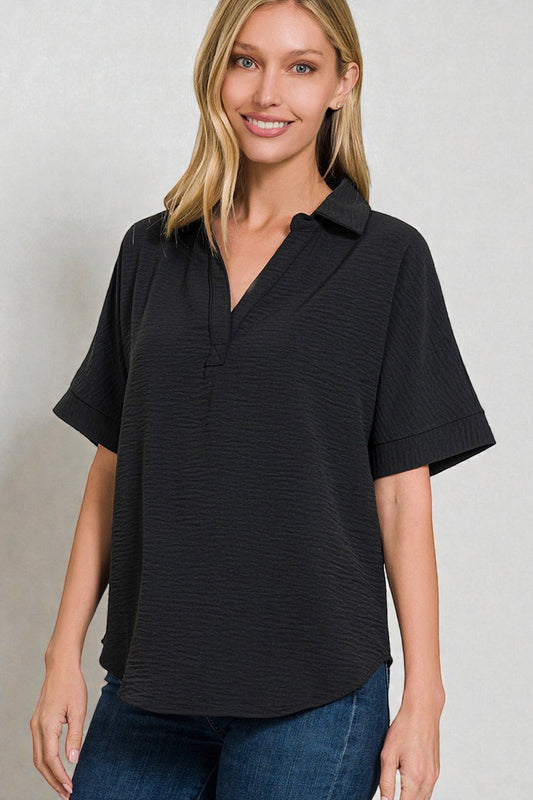 Woman wearing a black short-sleeve shirt with a collar against a plain background