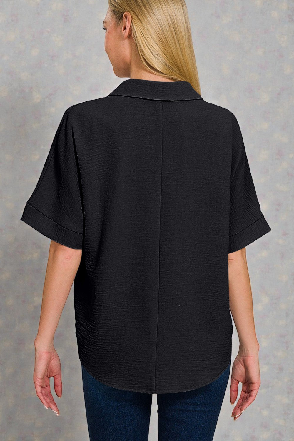 Person wearing a black shirt and blue jeans on a gray background