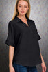 Woman wearing a black short-sleeve blouse against a gray background
