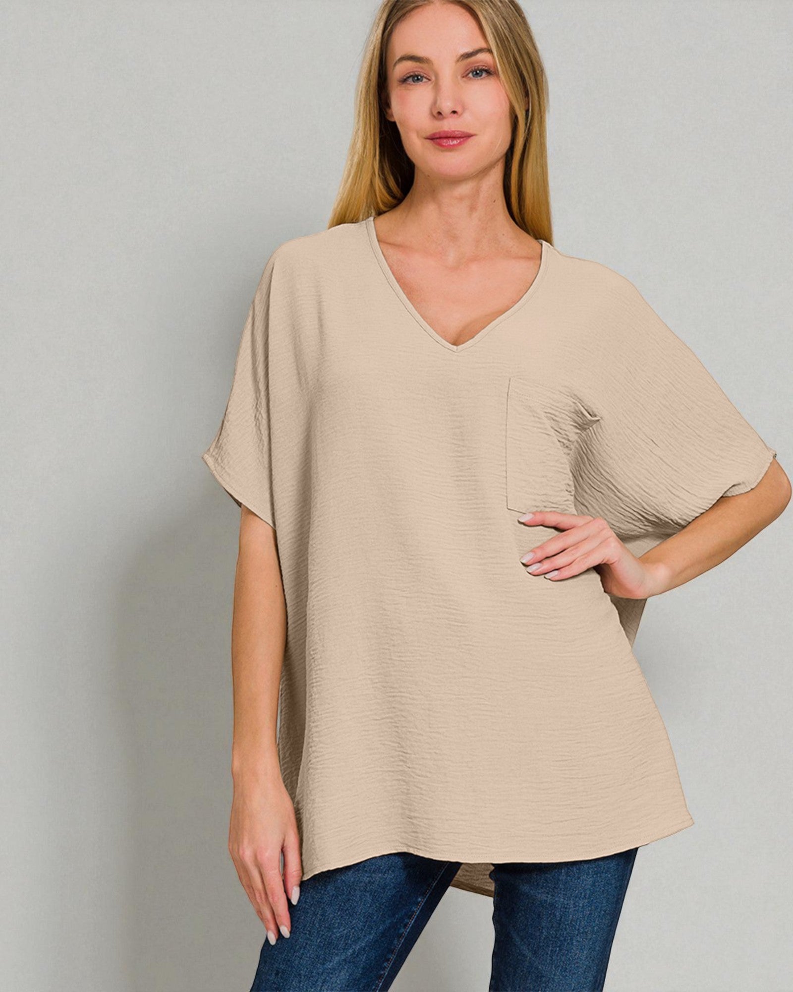 Woman wearing a beige oversized t-shirt with a pocket on a plain background