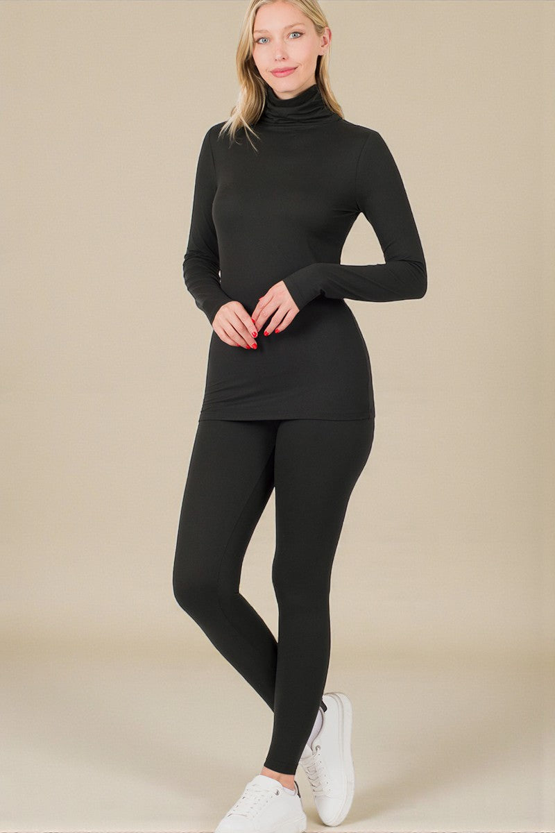 Woman wearing a black turtleneck top and leggings on a beige background