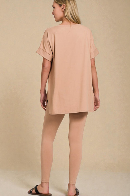 Woman wearing a beige tunic and leggings against a beige background