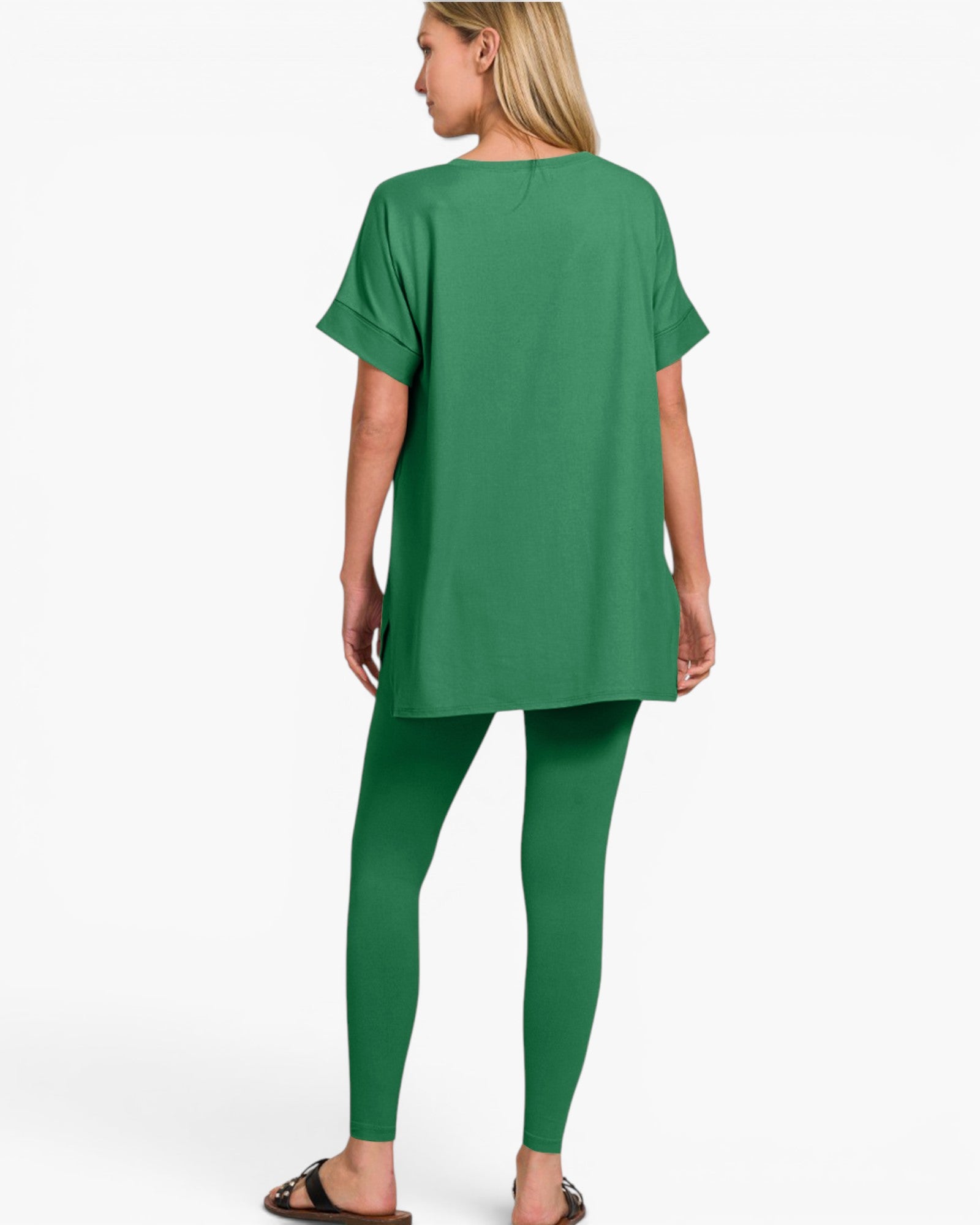A woman shown from the back wearing a matching green short-sleeve tunic top and leggings set, paired with dark brown sandals, against a plain white studio background.