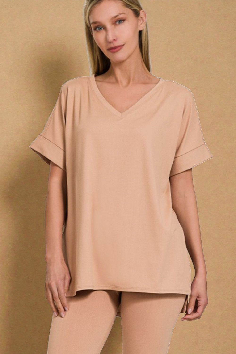 Woman wearing a beige oversized t-shirt and pants against a beige background