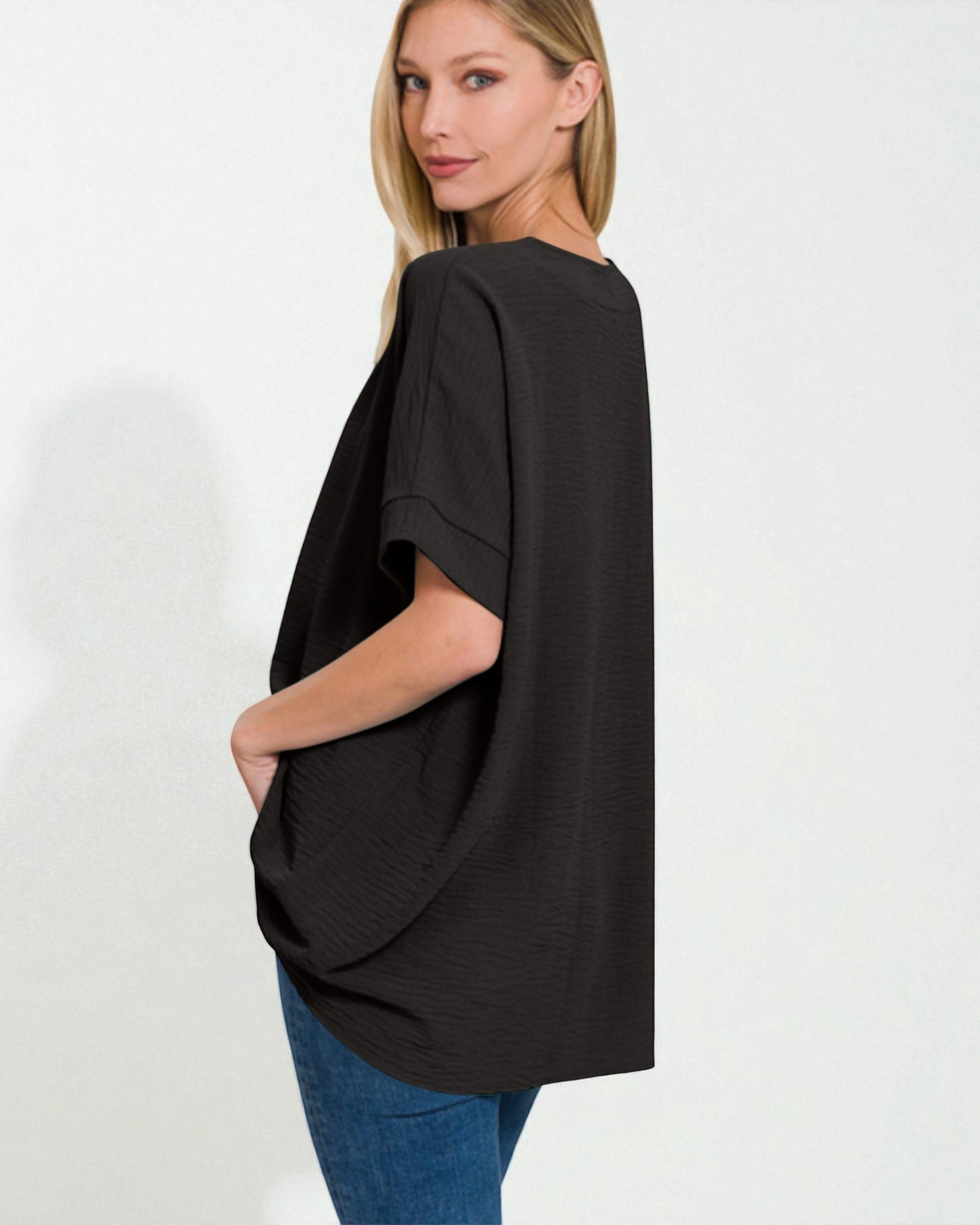 Woman wearing a black oversized top and blue jeans on a white background