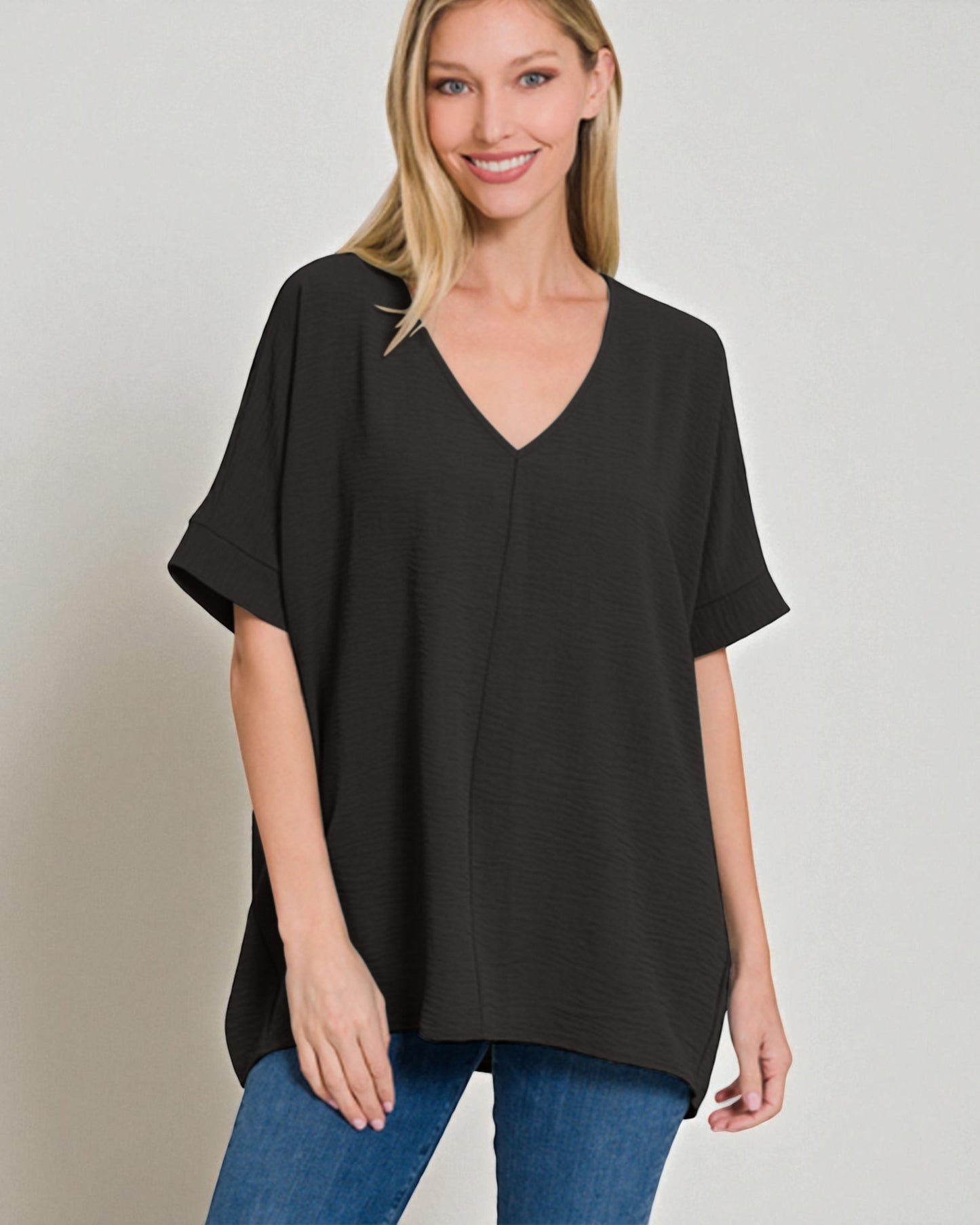 Woman wearing a black blouse with a plain background