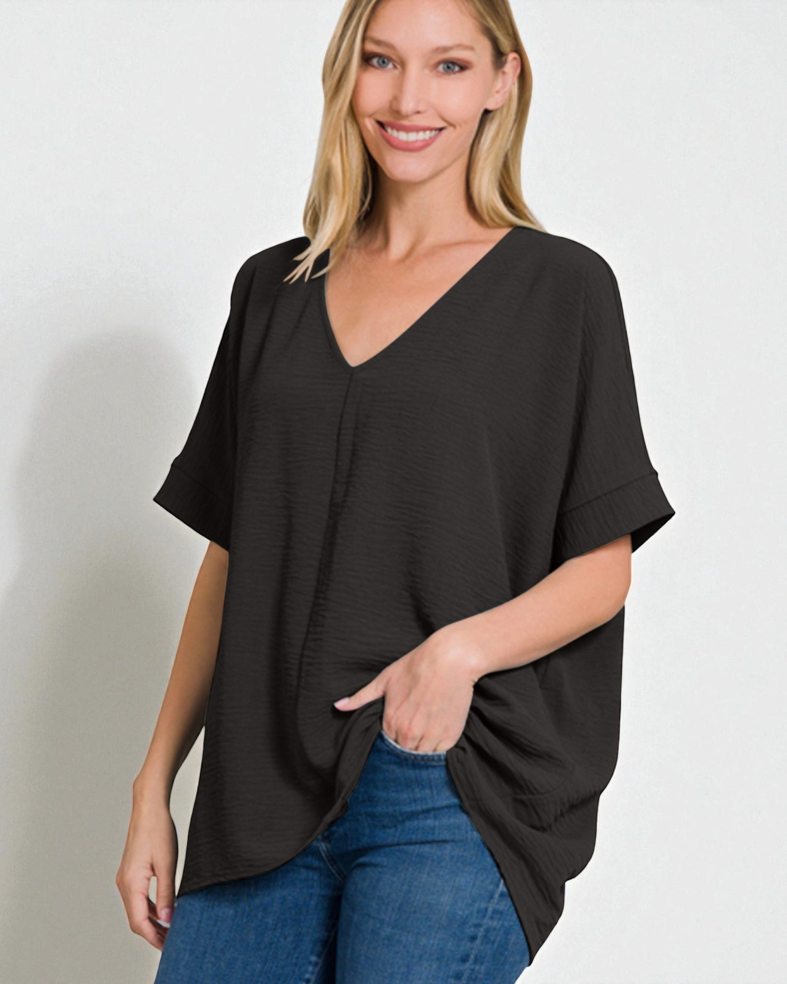 Woman wearing a black oversized top and blue jeans on a plain background