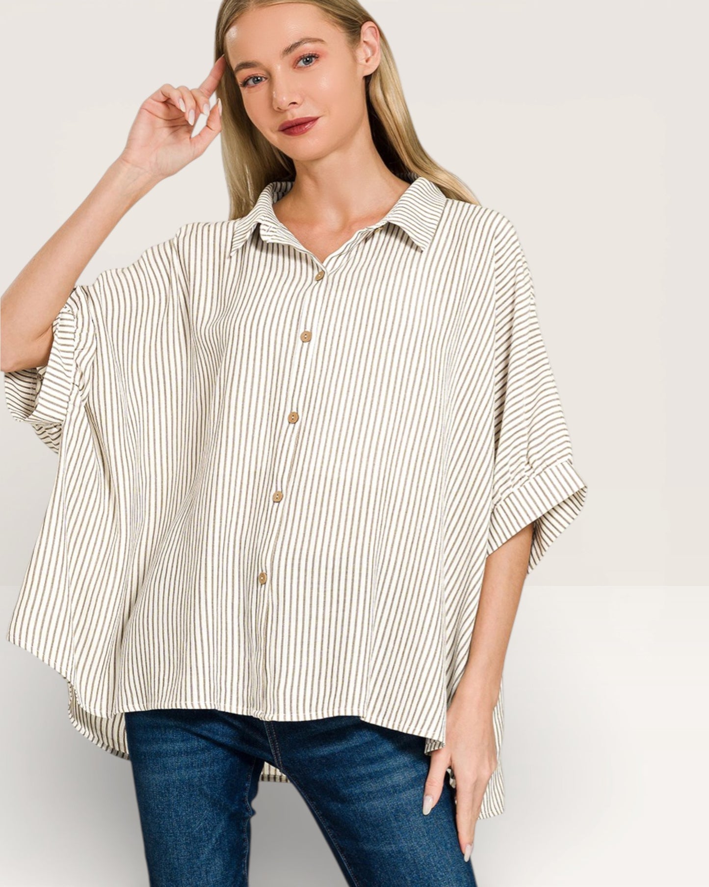 Woman wearing a striped shirt and jeans on a plain background