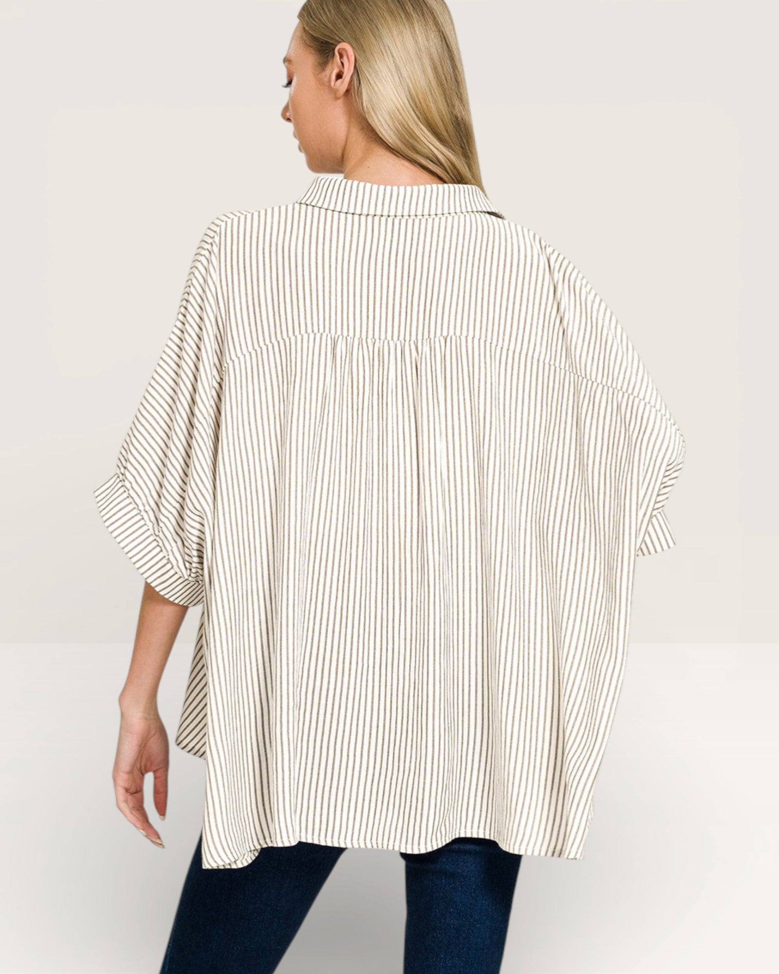 Woman wearing a loose-fitting, striped shirt on a plain background