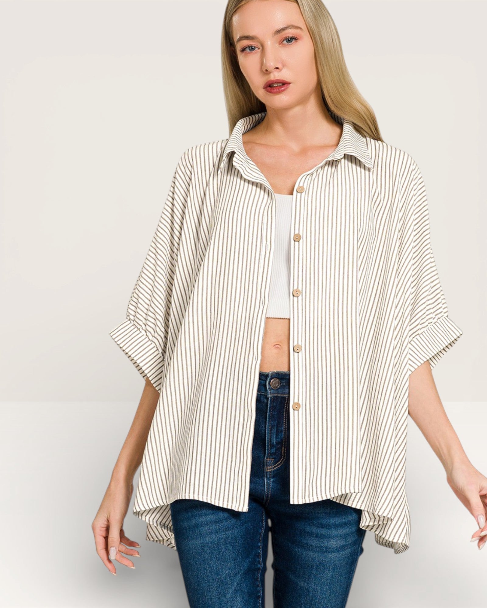 Woman wearing a striped shirt and jeans on a plain background