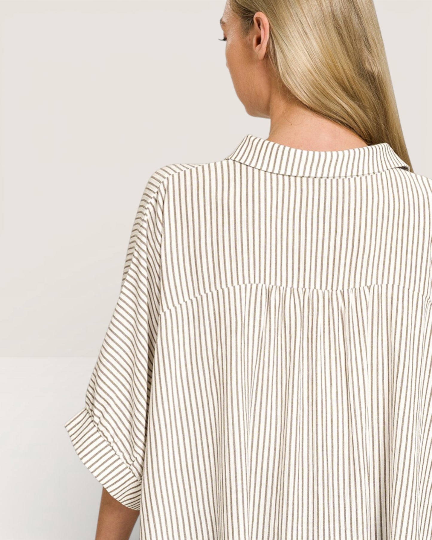 Woman wearing a beige and white striped shirt on a plain background