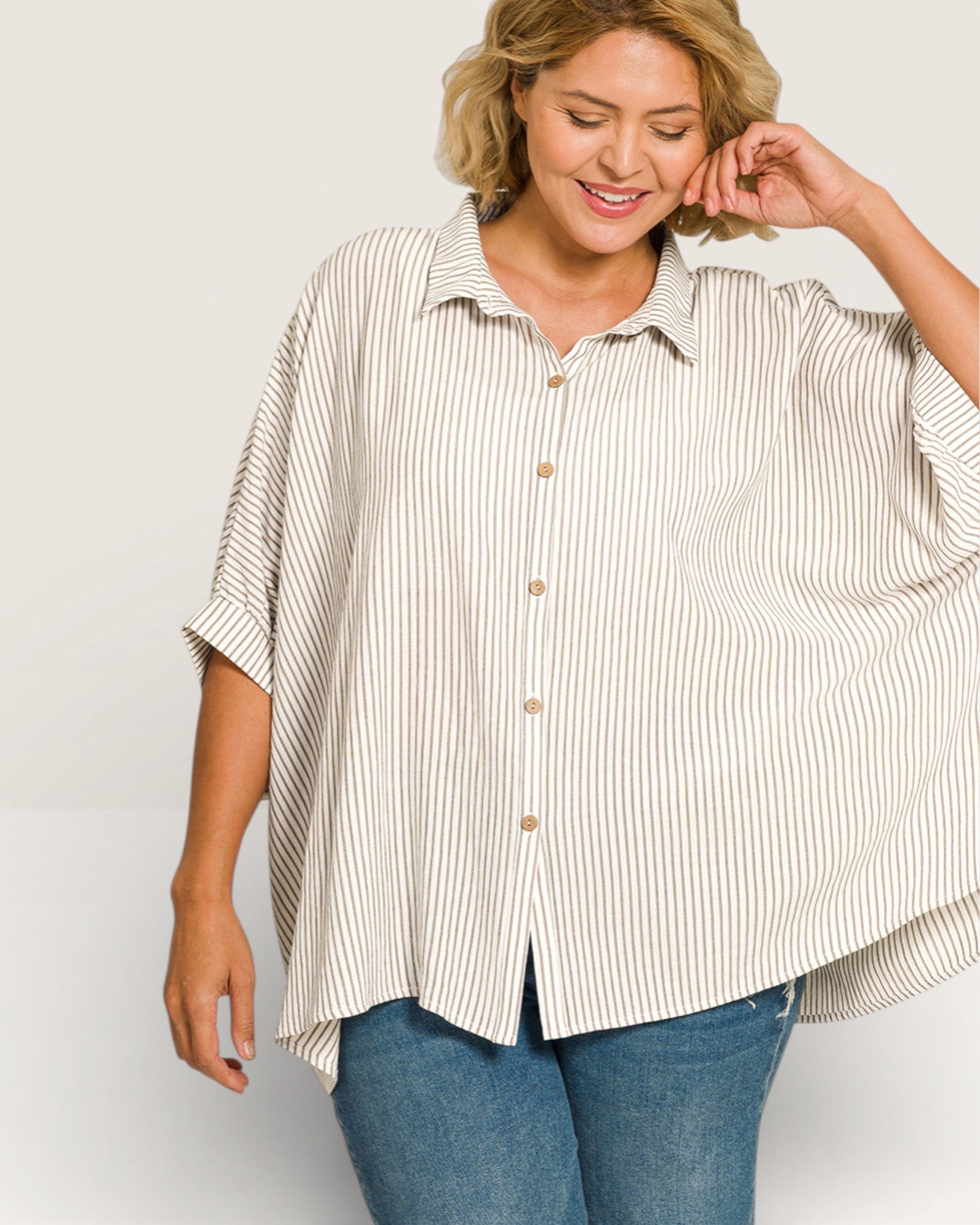 Woman wearing a striped shirt and jeans on a plain background