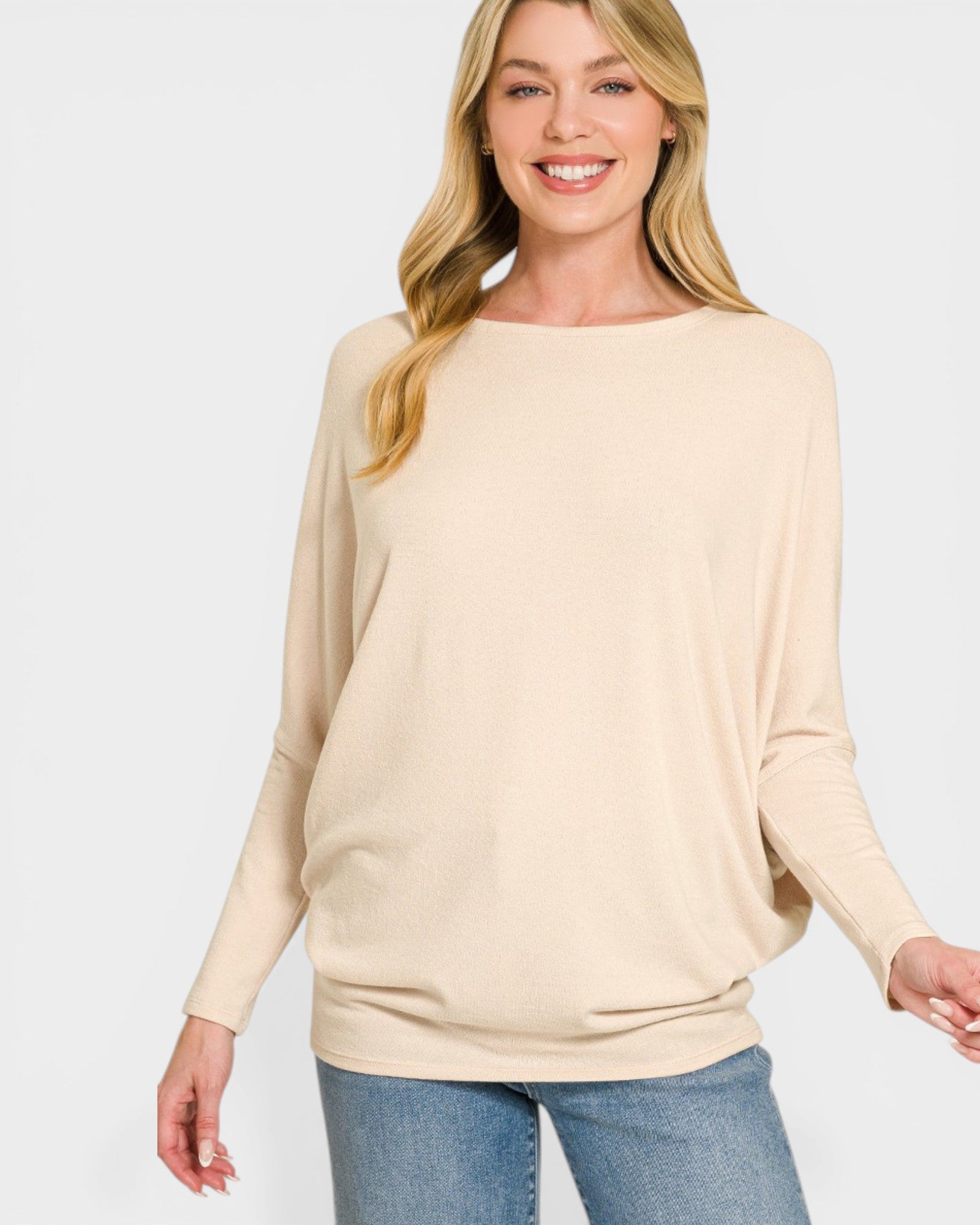 Woman wearing a beige sweater and blue jeans on a white background