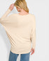 Woman wearing a beige long-sleeve top and blue jeans on a white background