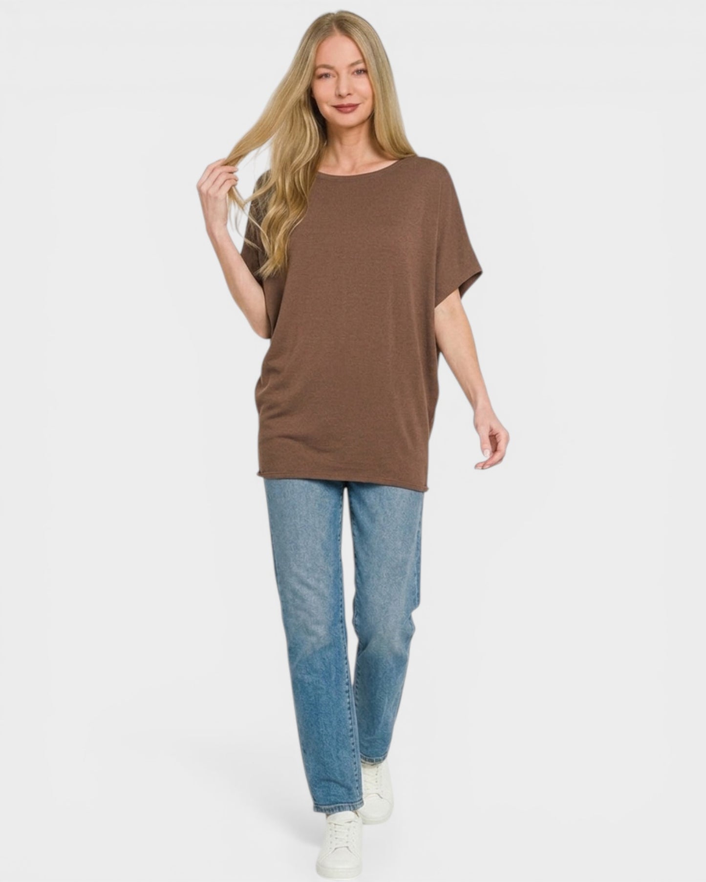 Woman wearing a brown oversized t-shirt and blue jeans on a white background