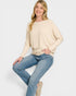 Woman wearing a beige sweater and blue jeans on a white background