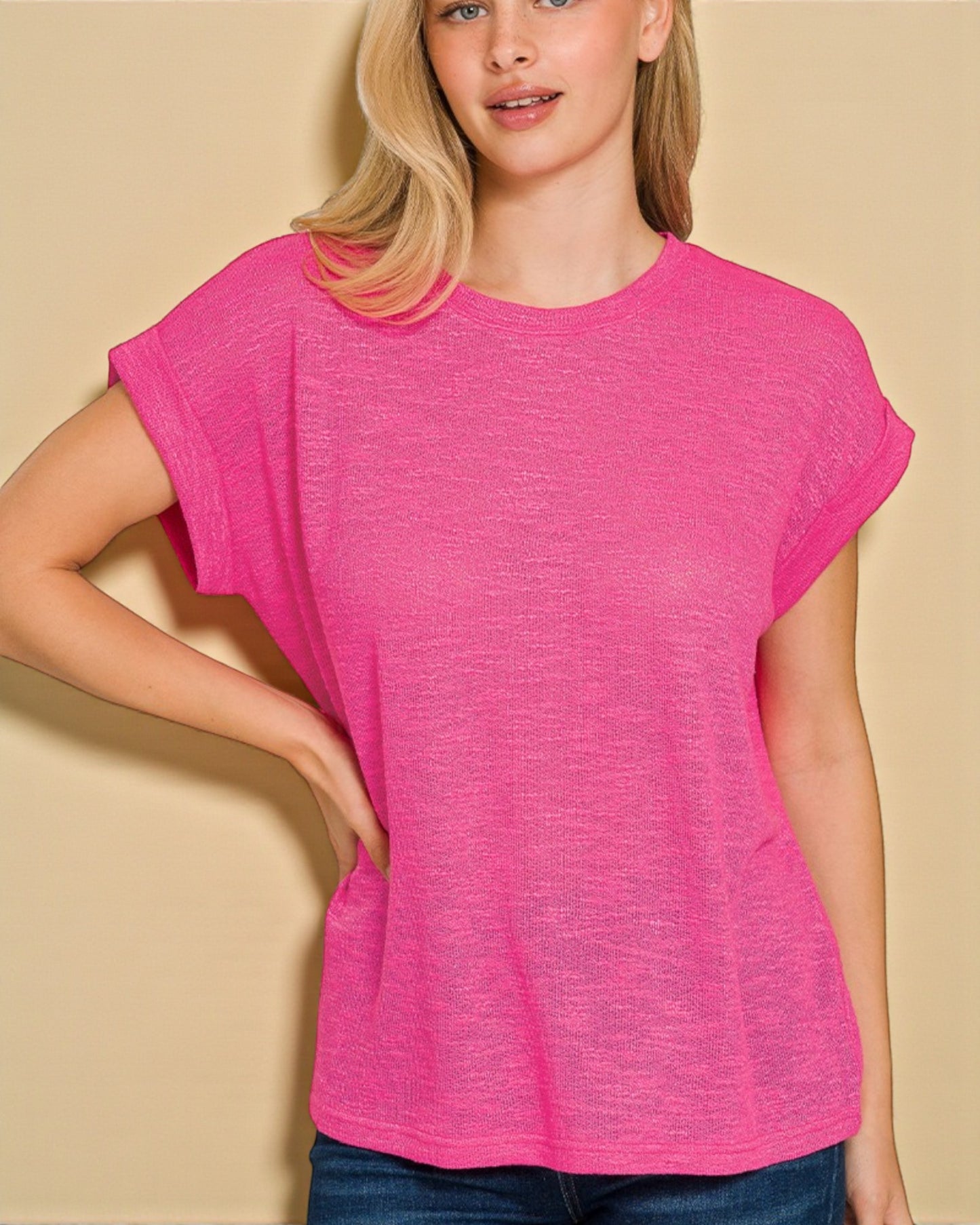 Woman wearing a bright pink t-shirt against a beige background