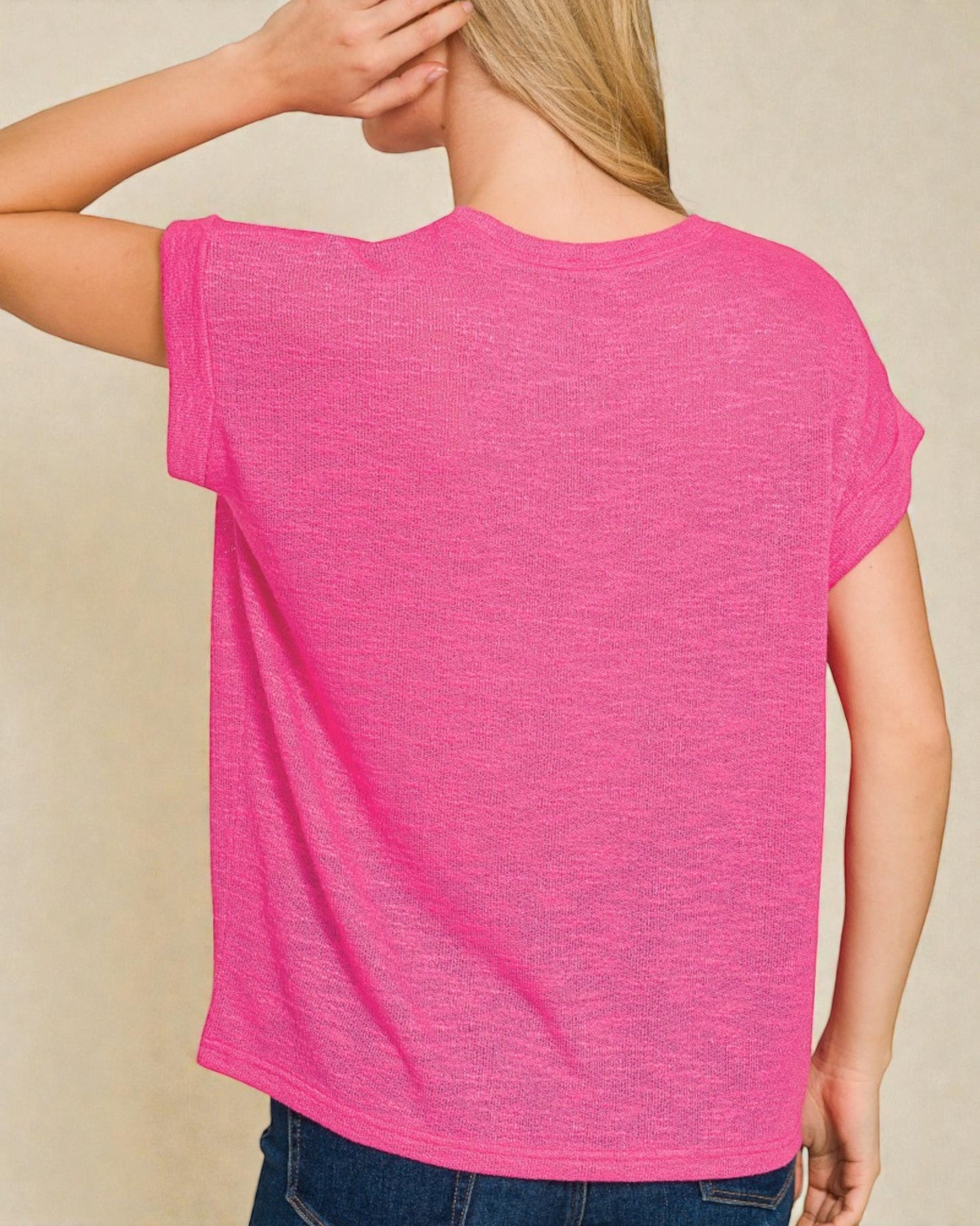 Person wearing a bright pink t-shirt against a beige background