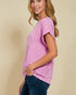 Woman wearing a pink t-shirt and blue jeans against a beige background