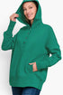 A woman wearing a bright green pullover hoodie with a buttoned henley neckline, front pockets, and a relaxed fit, paired with blue jeans against a plain light background.