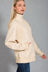 Woman wearing a beige fleece jacket against a gray background