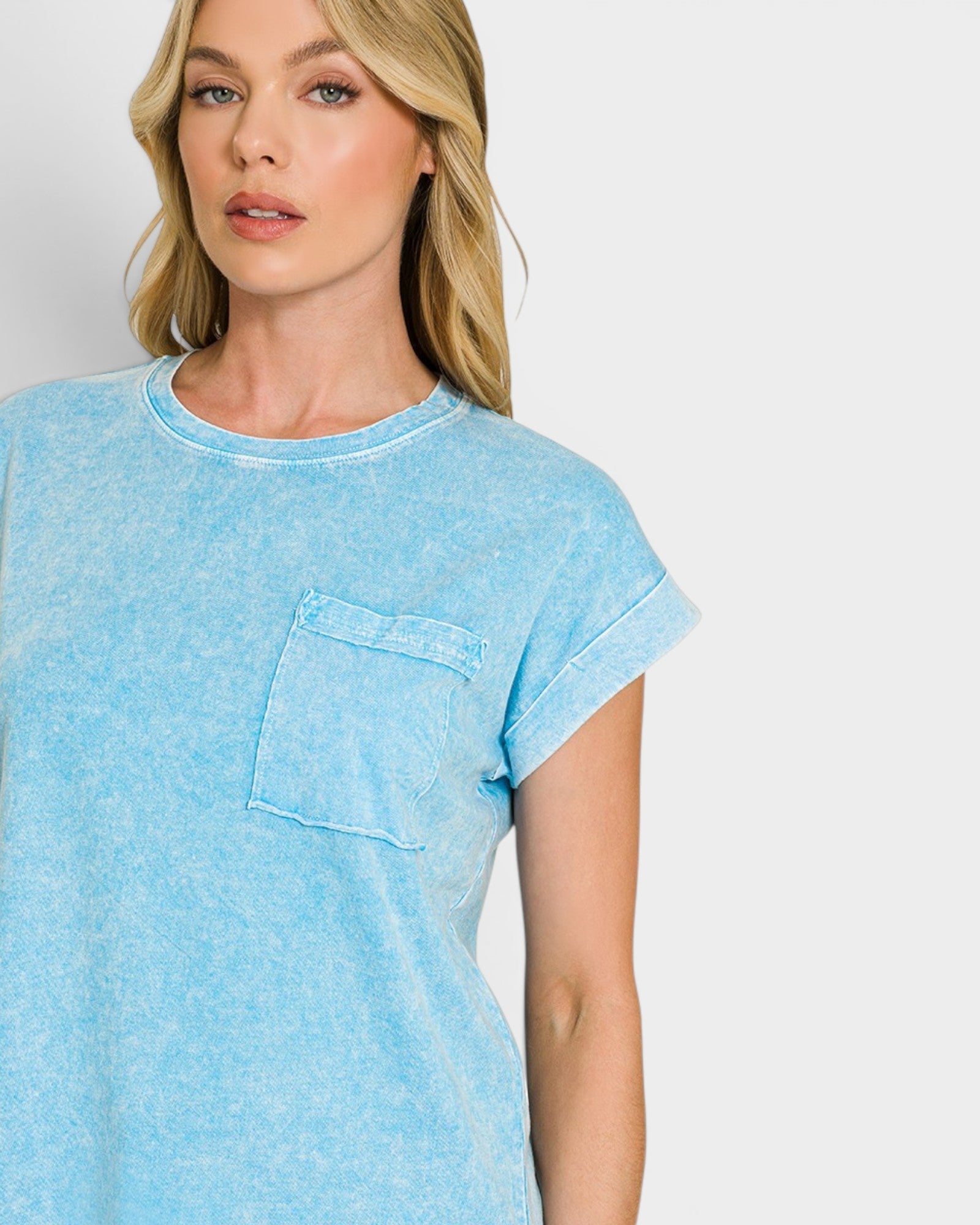 Woman wearing a light blue t-shirt with a pocket on a plain background