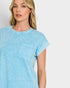 Woman wearing a light blue t-shirt with a pocket on a plain background