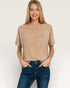 Woman wearing a beige t-shirt and blue jeans on a plain background