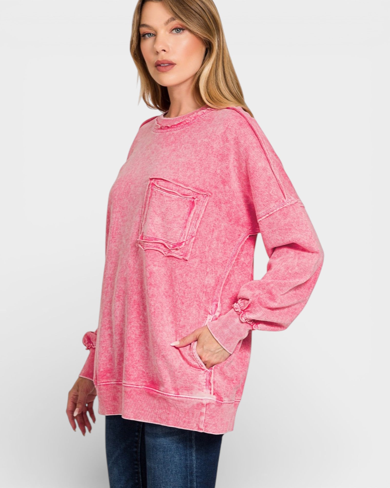 Woman wearing a pink sweatshirt with a pocket on a white background