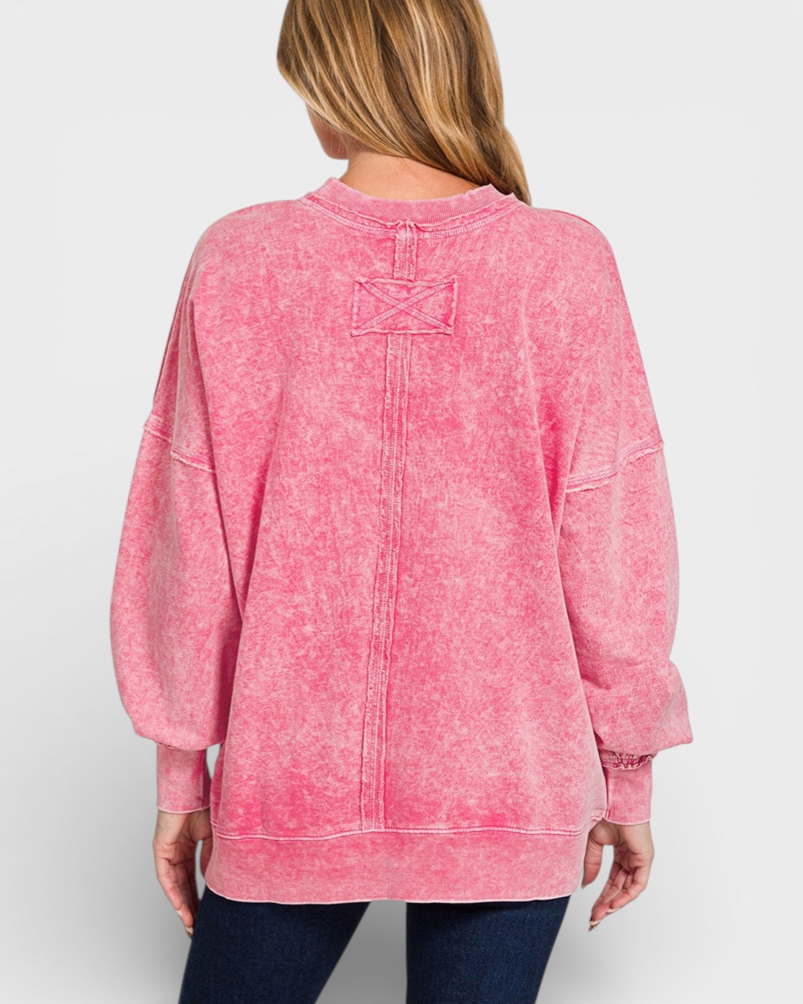 Pink acid-wash sweatshirt worn by a person on a white background