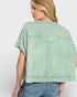 Woman wearing a green acid-wash shirt and blue jeans on a white background
