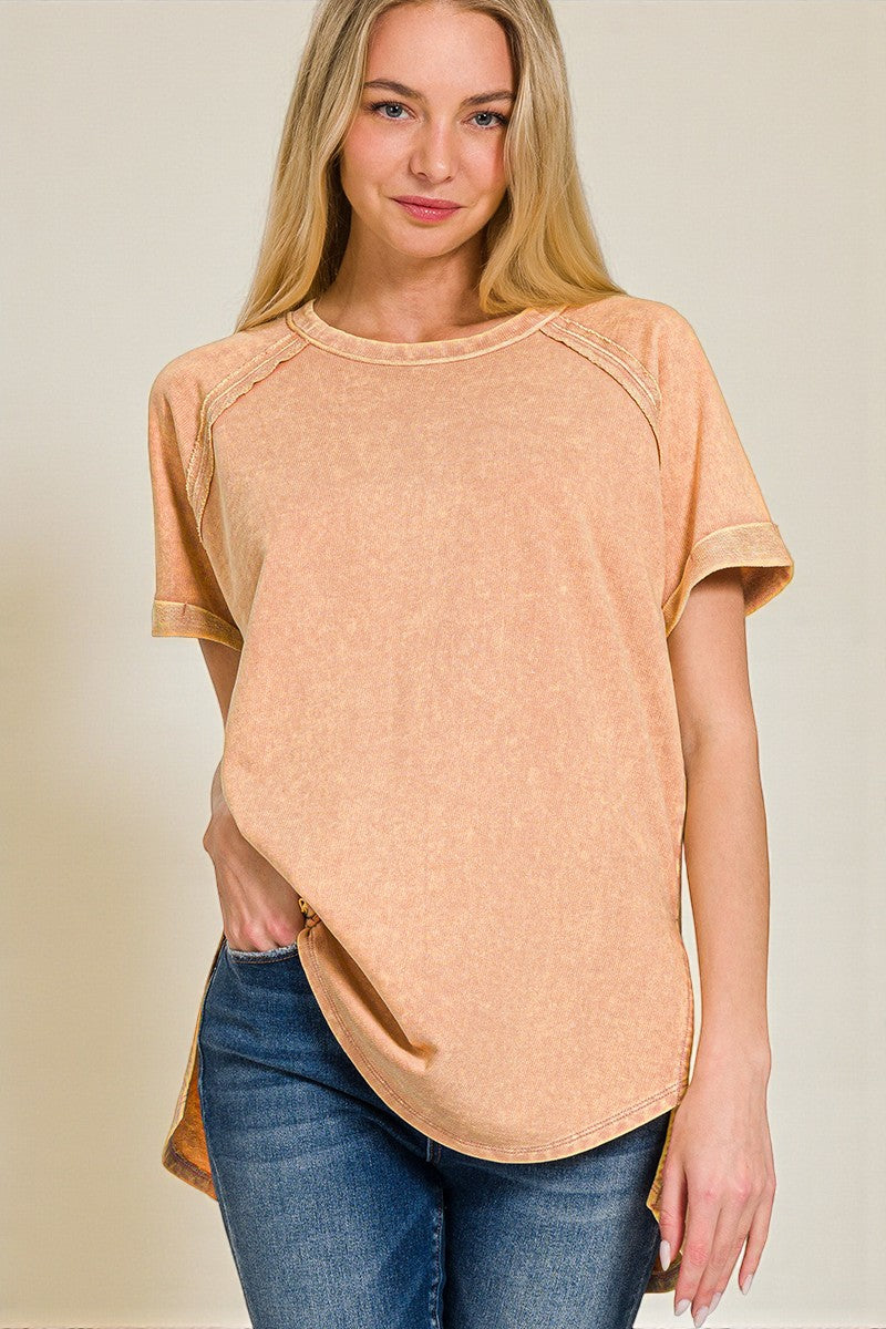 Woman wearing a peach-colored t-shirt and blue jeans against a beige background