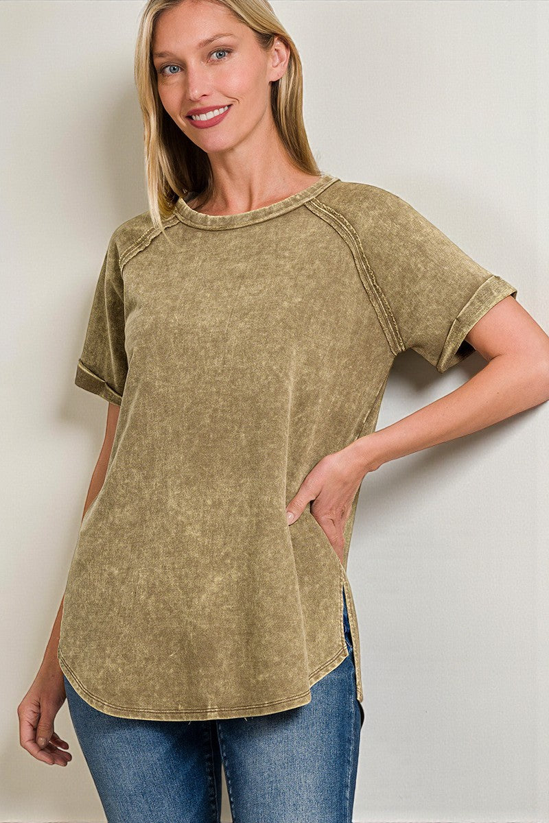 Woman wearing a green t-shirt and blue jeans against a plain background