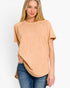 A woman wearing a short-sleeve, crew-neck t-shirt in a washed peach-beige color, paired with blue jeans, against a plain white background.