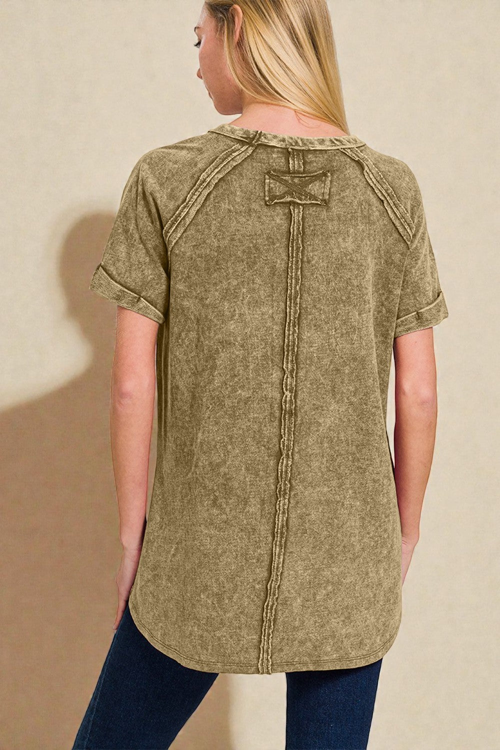 Woman wearing a green distressed denim shirt against a beige background