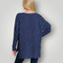 Person wearing a blue knitted cardigan against a plain background