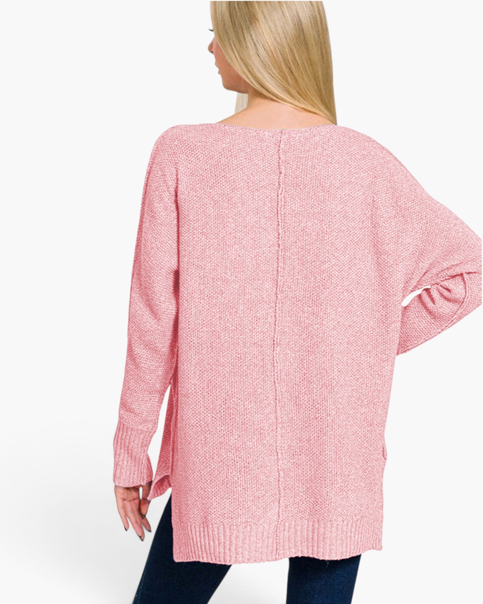 A woman shown from the back wearing a pink knit sweater with a wide boat neckline, long sleeves, and a relaxed fit, paired with dark blue jeans against a plain white studio background.