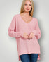 Woman wearing a pink sweater against a plain background