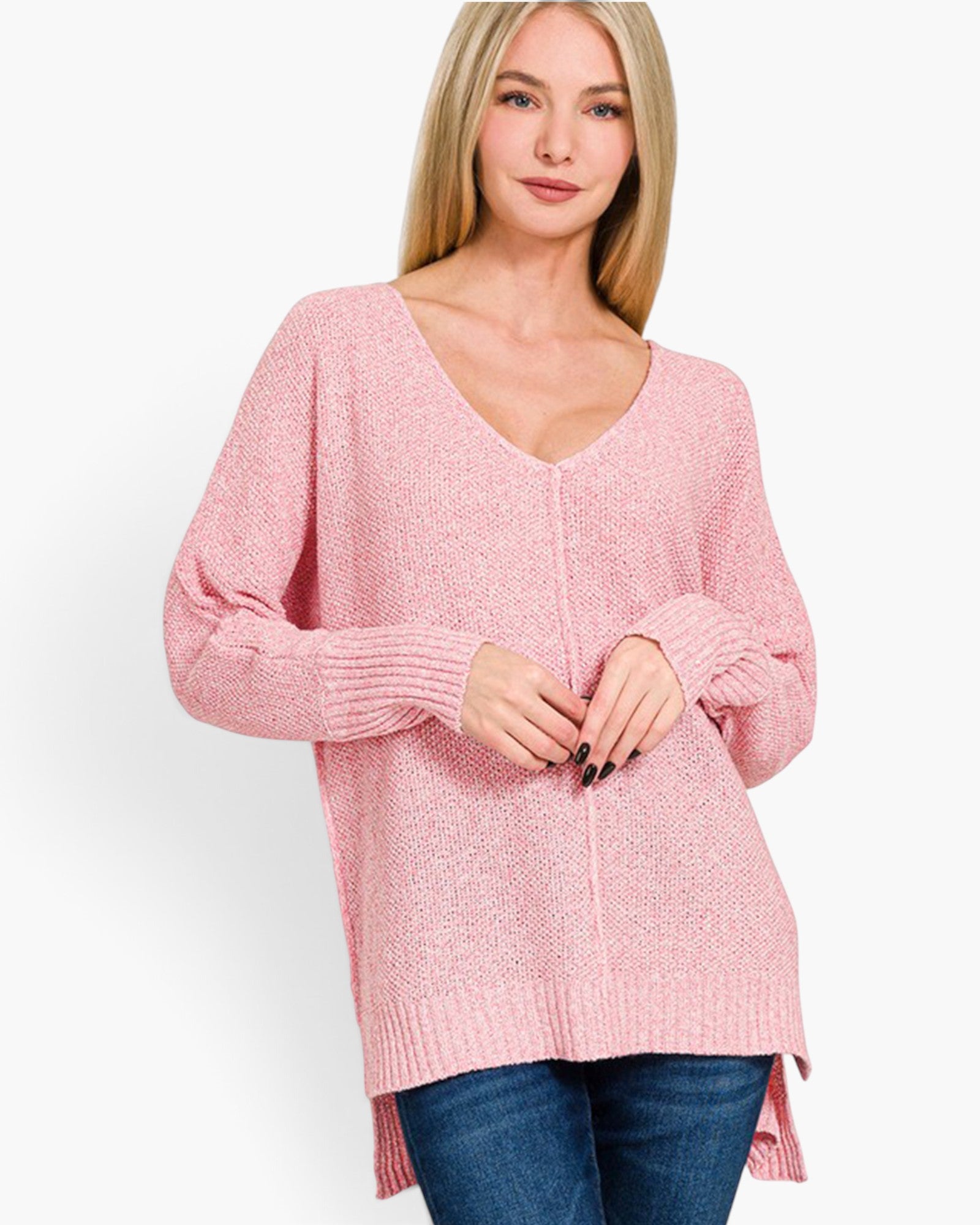 A woman wearing a pink knit sweater with a V-neck and long sleeves, paired with blue jeans, against a plain white background.
