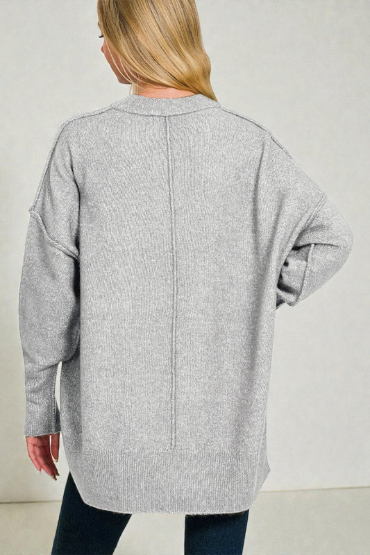 Person wearing a gray cardigan against a plain background