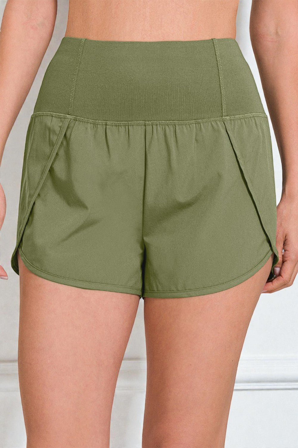 Green athletic shorts worn by a person on a light gray background