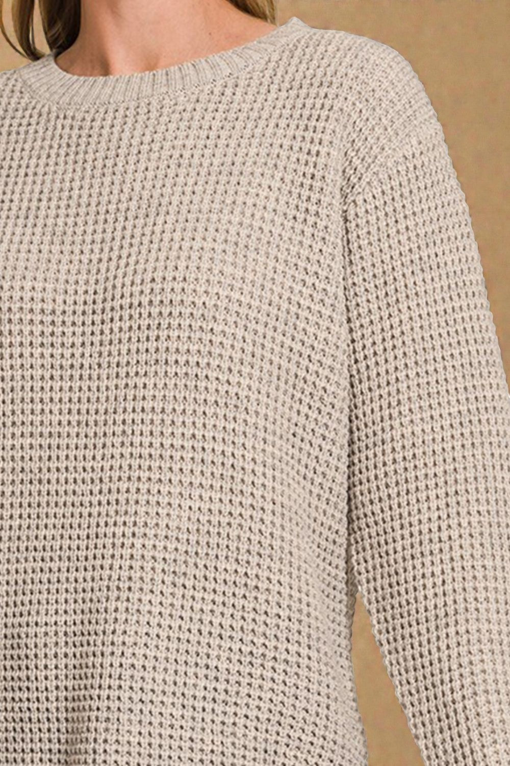 Close-up of a beige knitted sweater on a plain background