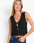 A woman modeling a black sleeveless knit vest with a split V-neck and front tie detail, paired with blue jeans against a plain white studio background.