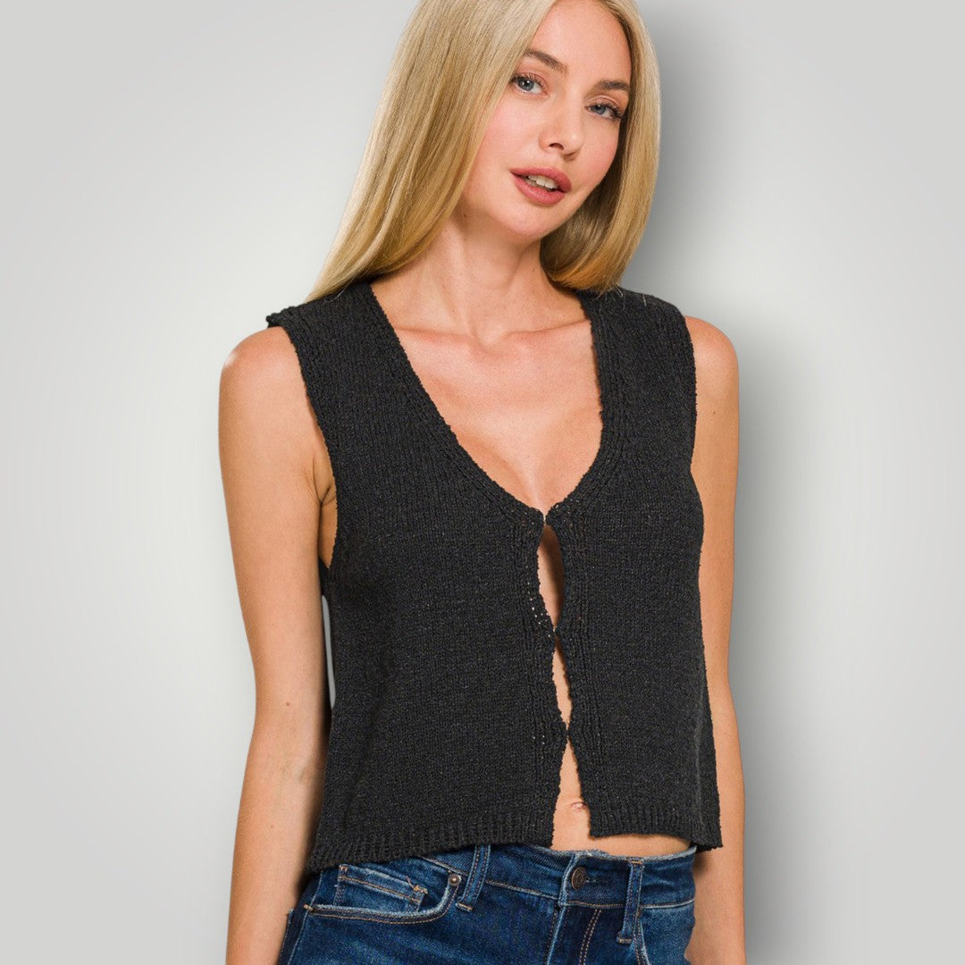 Woman wearing a black sleeveless knitted top against a plain background