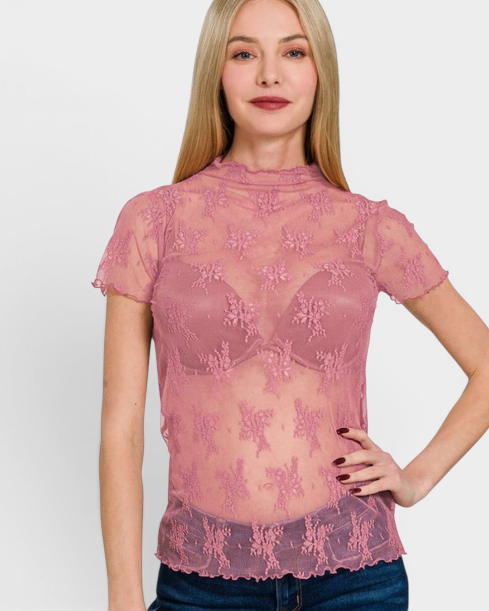 Woman wearing a pink lace top against a plain background