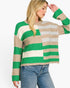 A woman wearing a chunky knit sweater with horizontal stripes in green, beige, and light gray, paired with blue jeans, against a plain white background.