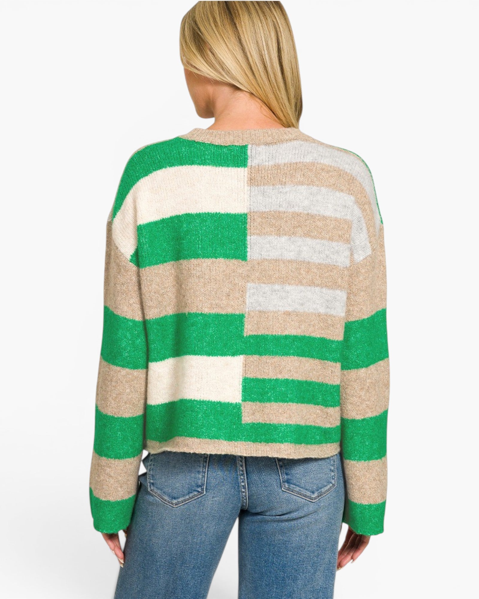 A woman viewed from the back wearing a knit sweater with wide horizontal stripes in green, beige, cream, and light gray, paired with blue jeans against a plain white background.