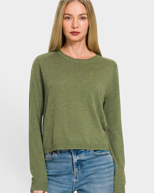 Woman wearing a green sweater and blue jeans on a white background