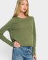 Woman wearing a green sweater and blue jeans on a white background